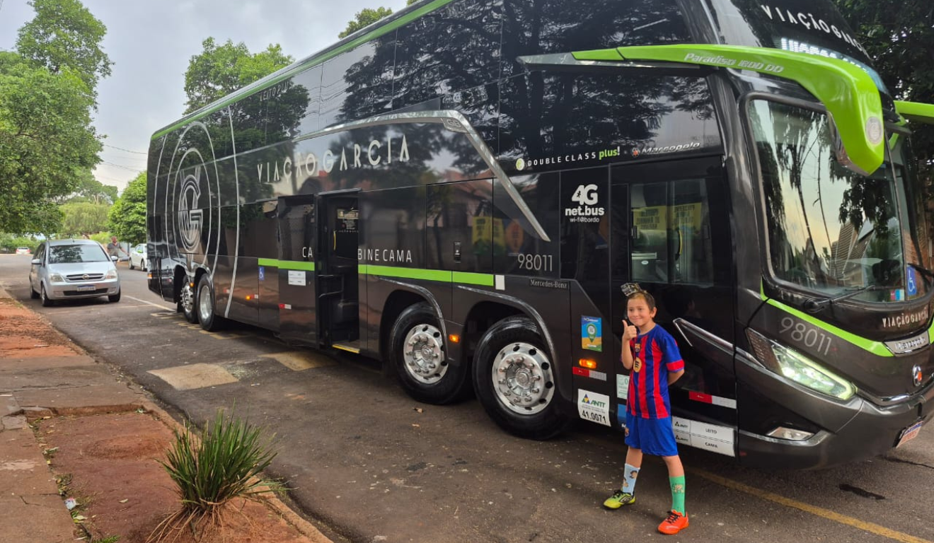 João Gabriel, de 10 anos, com uma réplica de um ônibus preto e dourado G8 da Viação Garcia, modelo que celebra os 90 anos da empresa.