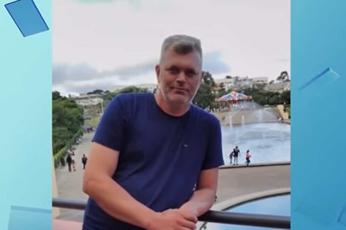 Homem de meia idade posando para a foto vestindo camisa azul escura