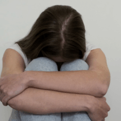 Um homem foi preso por tentar abusar de uma mulher em uma obra. Na imagem ilustrativa, vemos uma mulher sentada e cabisbaixa, escondendo o rosto em sua perna.