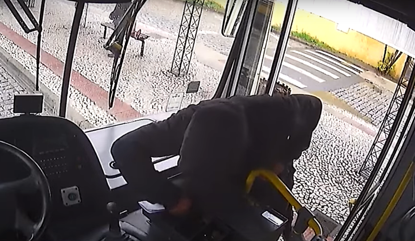 Um homem furtou dinheiro de um ônibus em Curitiba. Na imagem, vemos o momento em que o homem, vestindo um moletom preto e com capuz sobre a cabeça, está retirando o dinheiro do caixa cobrador.