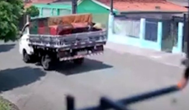 Caminhão passando pela rua no momento em que homem é morto com tiro nas costas