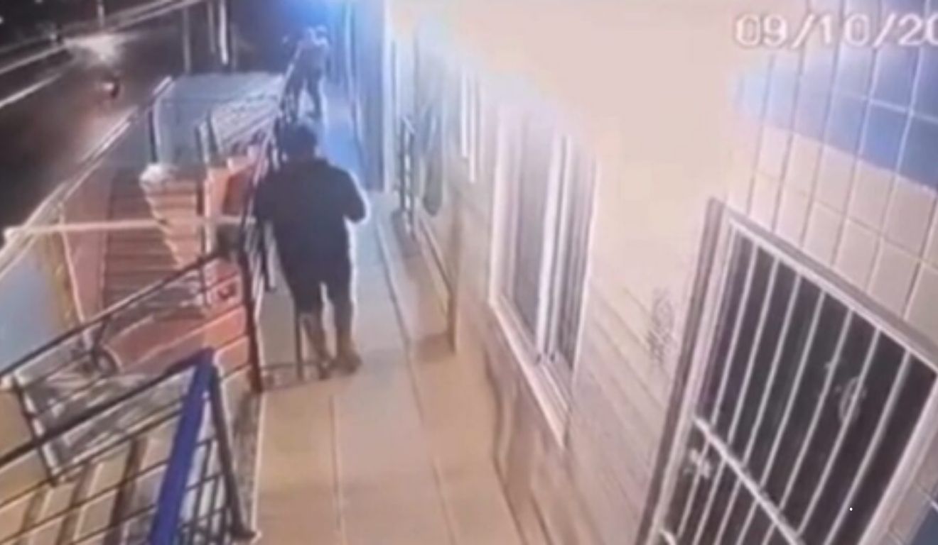 homem sendo morto a tiros enquanto segura bebê no colo