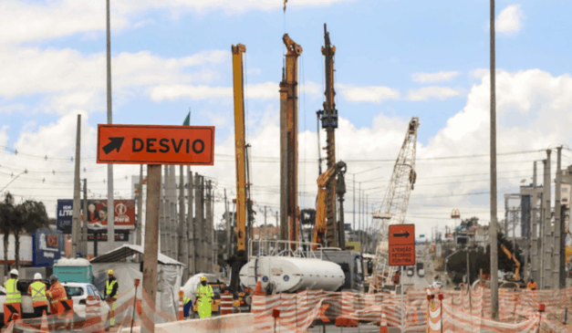Uma nova marginal da Victor Ferreira do Amaral será liberada neste domingo (26). Na imagem, vemos uma placa de desvio em primeiro plano, enquanto as obras da avenida aparecem ao fundo.