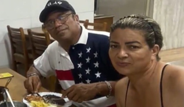 Mulher suspeita de matar marido com vitamina envenenada e marido ao lado dela em mesa de jantar