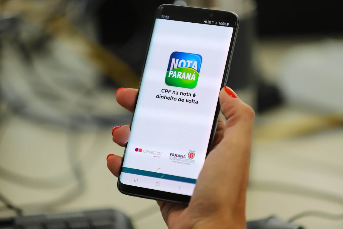 Mão segurando celular com o app do Nota Paraná na tela