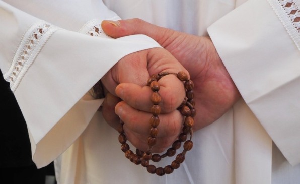 mãos de padre com terço