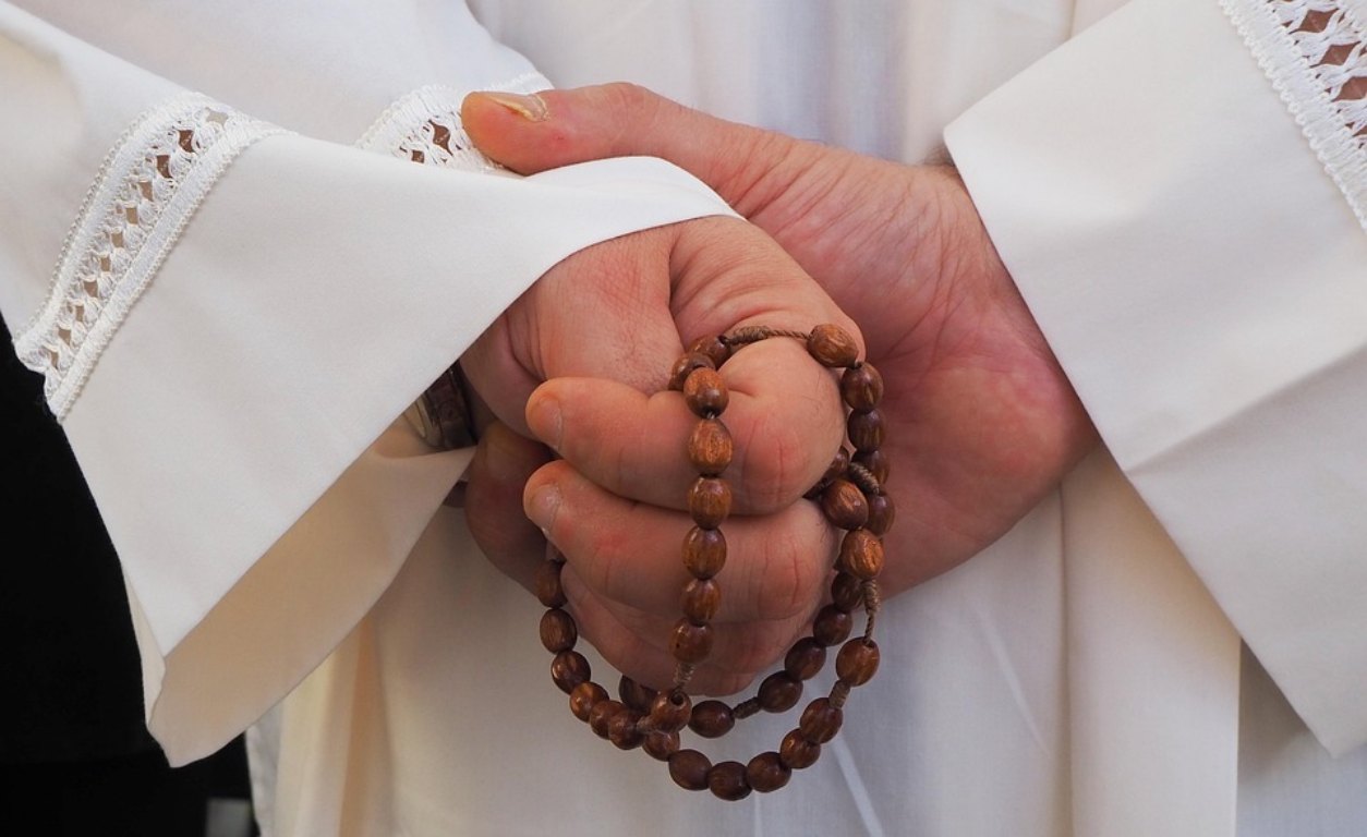 mãos de padre com terço 