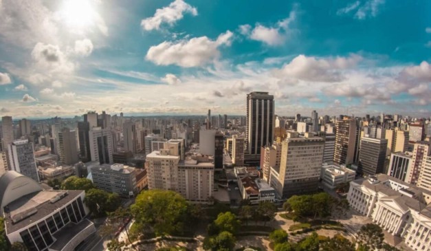 O Paraná apresenta um alto potencial para investimentos imobiliários. Na imagem, vemos uma vista aérea da cidade de Curitiba, sobrevoando a praça Santos Andrade.