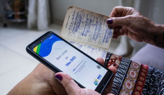 imagem de mulher segurando celular com aplicativo do meu INSS aberto