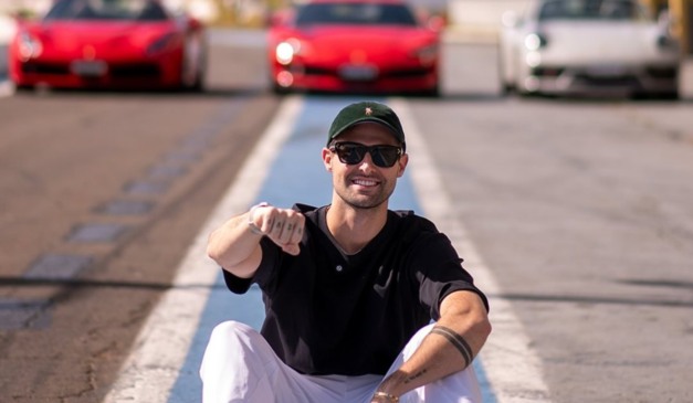 Rezende em frente a carros e sentado na pista