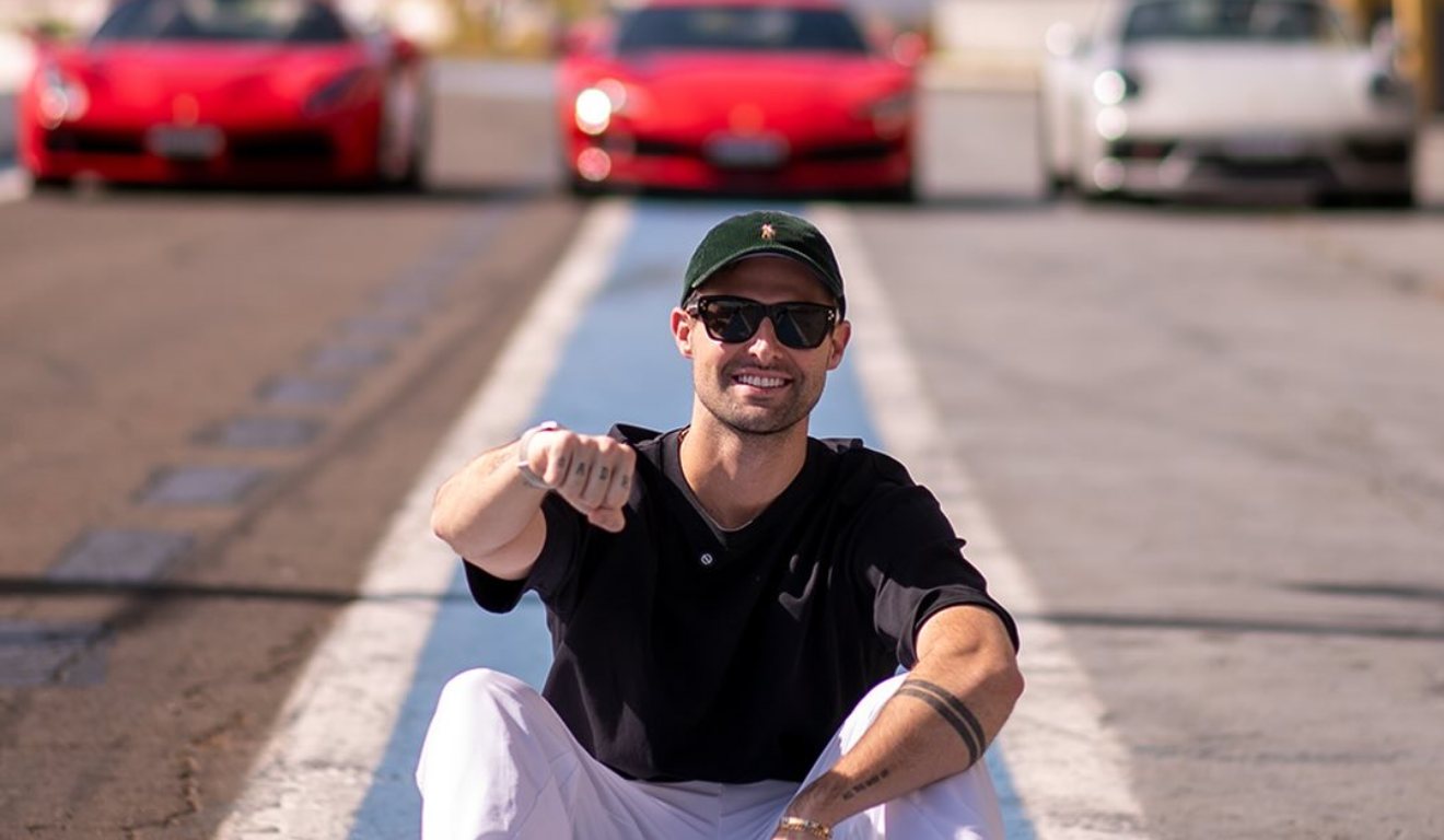 Rezende em frente a carros e sentado na pista