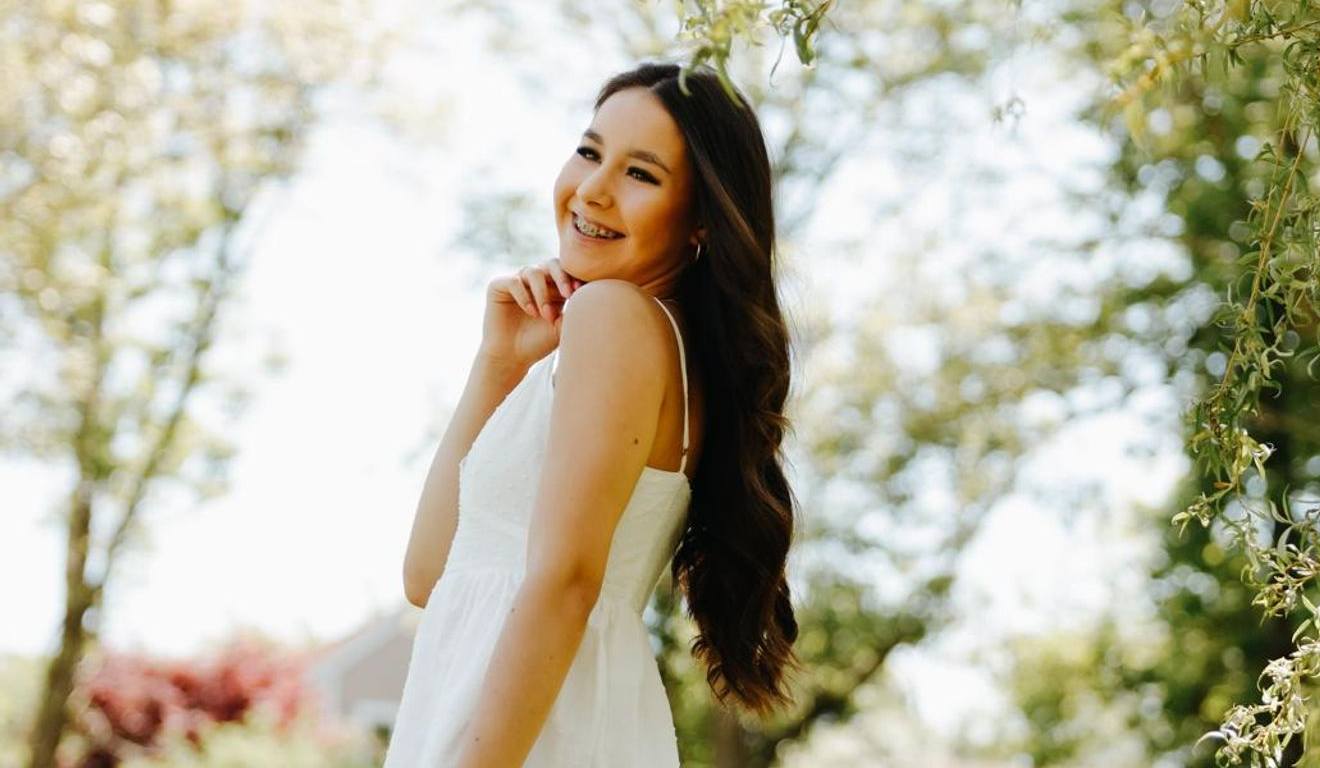 Anne Caroline Urbanski de Carvalho em foto de vestido branco em um parque dos Estados Unidos