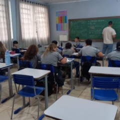 Sala de aula com alunos prestando atenção no professor