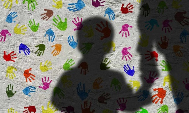 foto de sombra de criança sobre parede branca com impressões coloridas de pequenas mãos