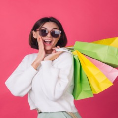 foto de moça jovem segurando sacolas de compras em fundo rosa