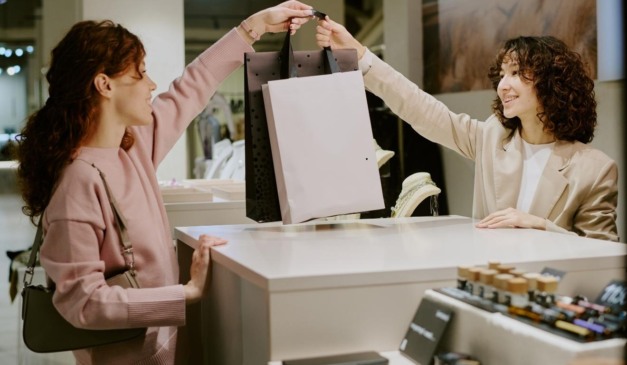 vendedora entregando sacola para cliente