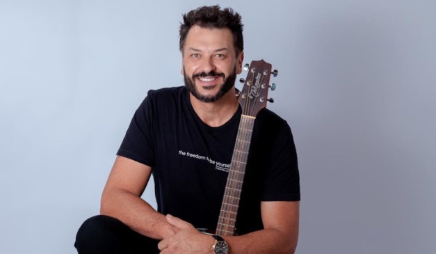 Cantor Ewerton Zanata em foto sentado com violão