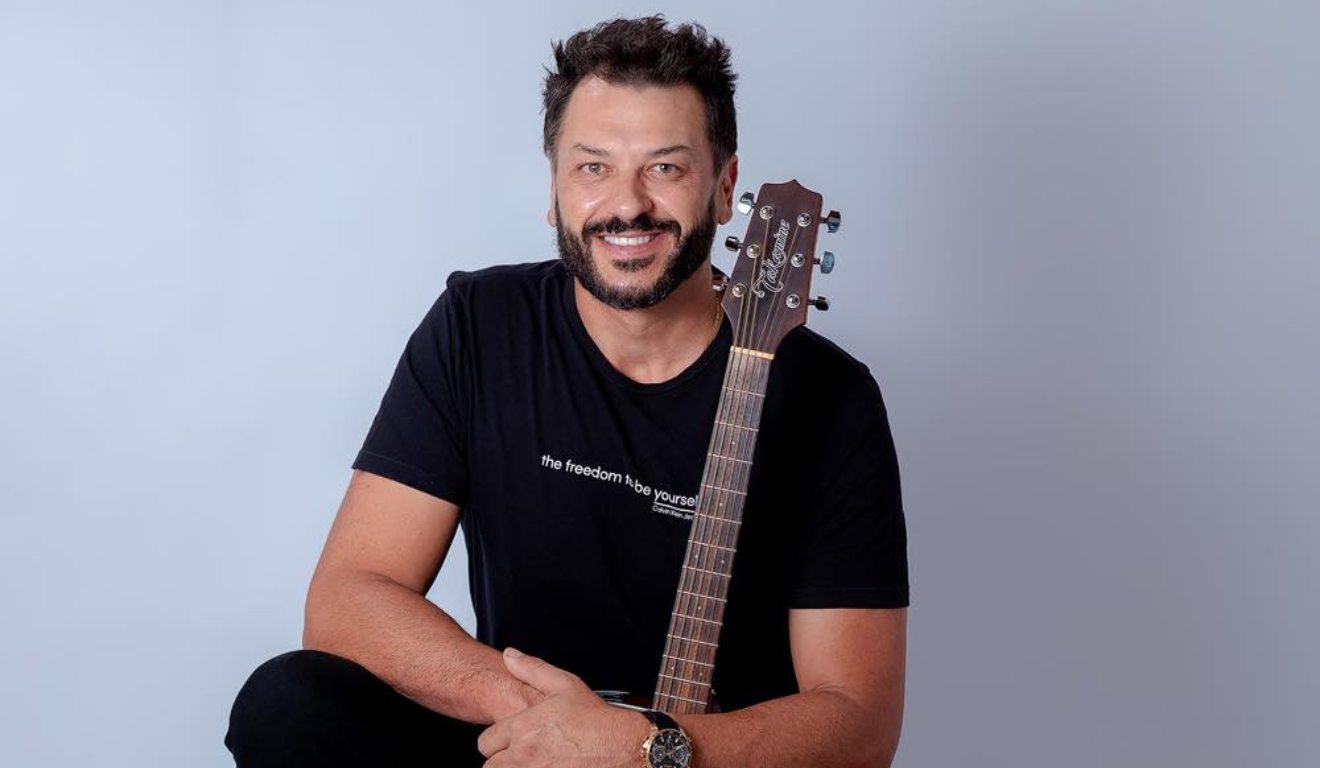 Cantor Ewerton Zanata em foto sentado com violão