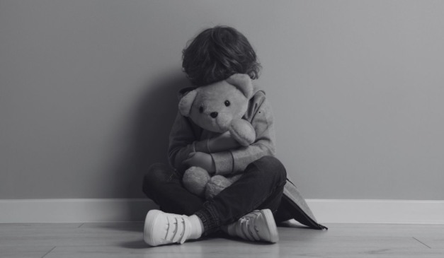 Casal é condenado pelo estupro da sobrinha. Na imagem ilustrativa, em preto e branco, vemos uma criança sentada com as pernas cruzadas, escondendo o rosto com um urso de pelúcia.