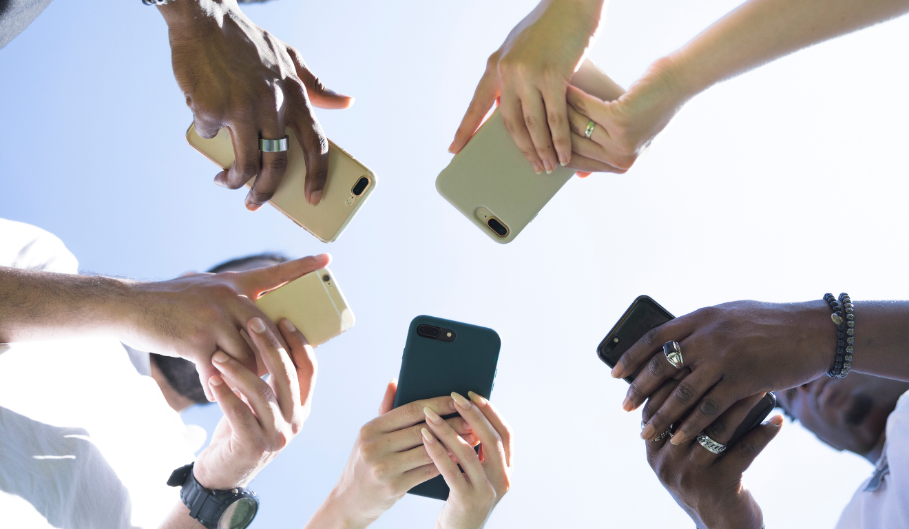 Confira celulares para comprar na Black Friday 2025 abaixo de R$ 2 mil. Na imagem, vemos diversas pessoas mexendo em diferentes modelos de celular.