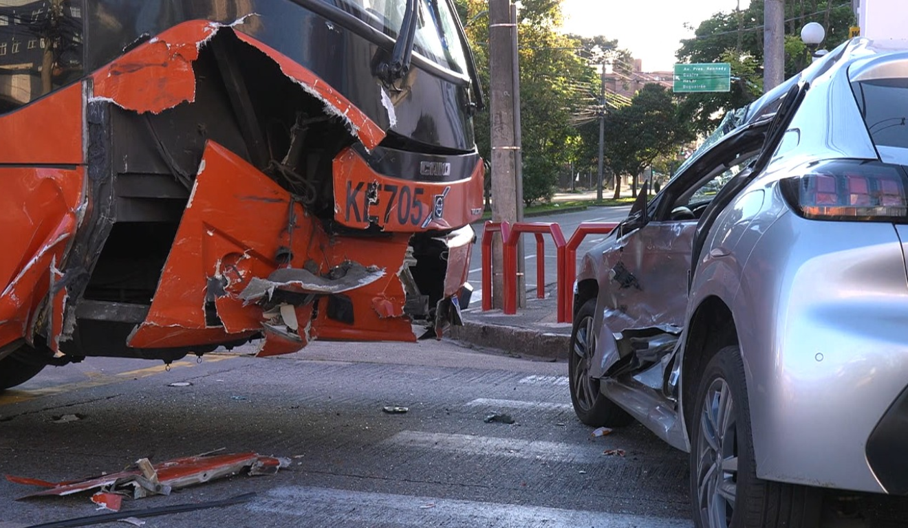 Um motorista fez uma conversão proibida e teve seu carro arrastado em Curitiba. Na imagem, vemos uma foto que mostra tanto a frente do ônibus quanto a lateral do carro danificadas.