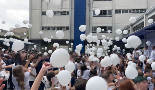 crianças com balões brancos para homenagem a estudante baleada em frente ao colégio