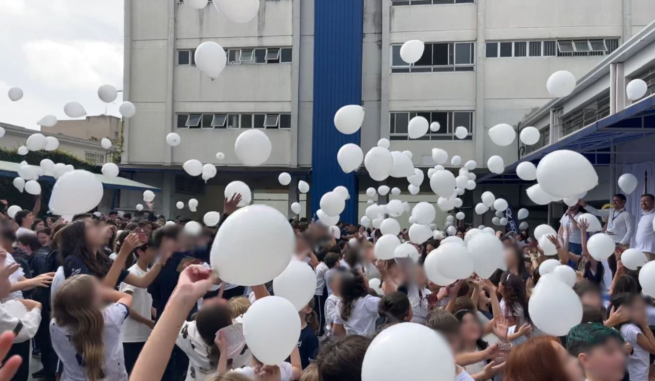 crianças com balões brancos para homenagem a estudante baleada em frente ao colégio