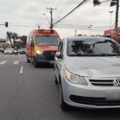 Estudantes foram atropeladas enquanto estavam mexendo celular. Na imagem, vemos o carro do acidente com o capô amassado, com uma ambulância do Corpo de Bombeiros logo atrás.