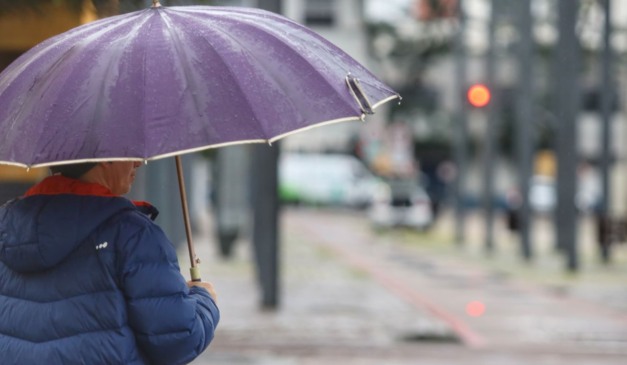 pessoa andando com guarda-chuva para ilustrar a chegada da frente fria no paraná