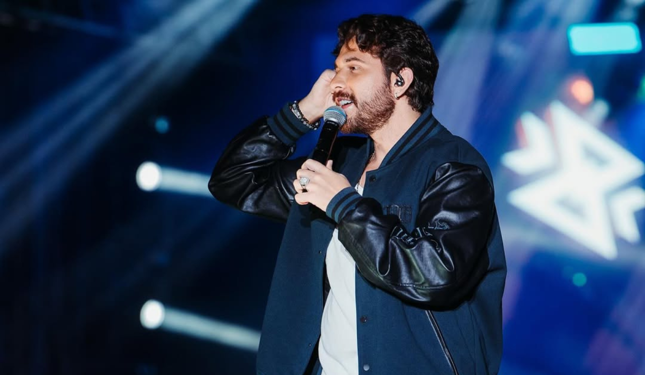 Imagem de Gustavo Mioto cantando.