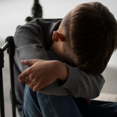 Criança com a cabeça baixa na cama