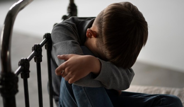 Criança com a cabeça baixa na cama