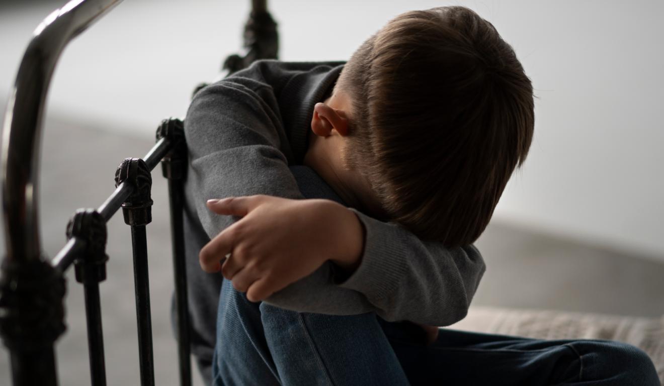 Criança com a cabeça baixa na cama