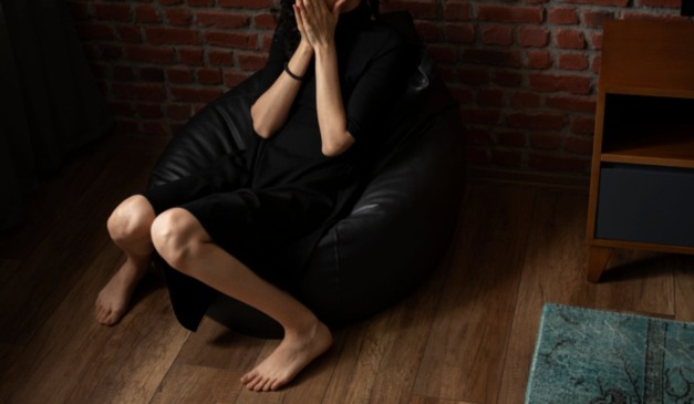 Jovem sozinha chorando em sofá de casa