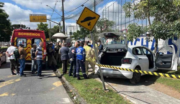 Moradores e agentes de segurança perto do veículo com motorista morto dentro
