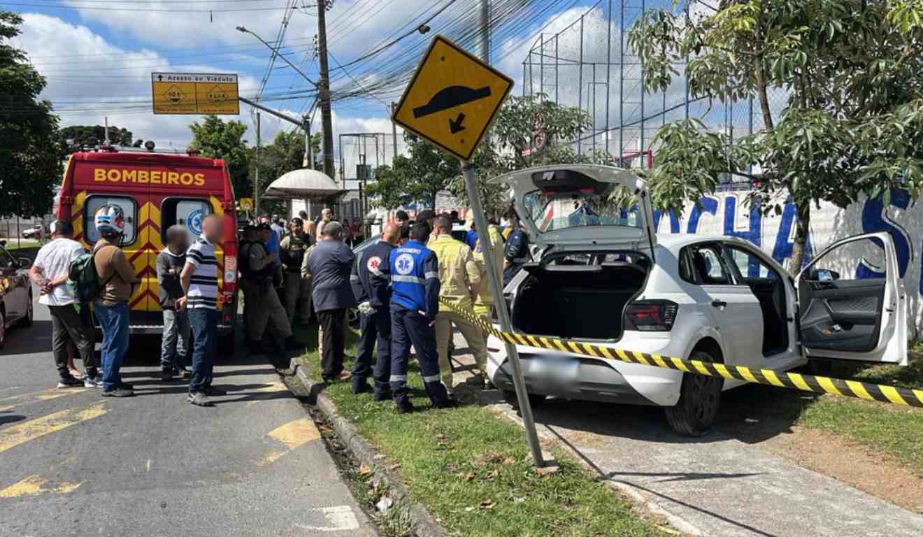 Moradores e agentes de segurança perto do veículo com motorista morto dentro