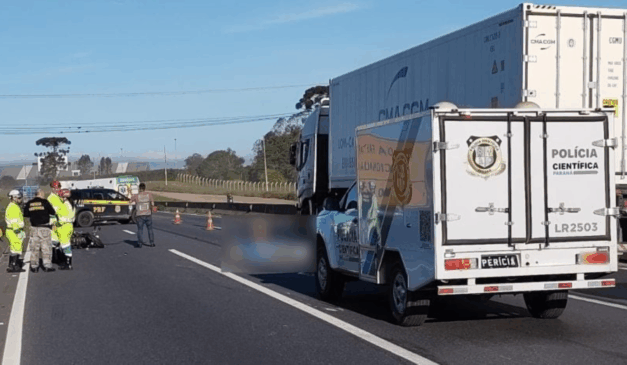 Um motociclista morreu atropelado por um caminhão na Grande Curitiba. Na imagem, vemos a rodovia, com o corpo no chão, borrado para preservar o anonimato da vítima.
