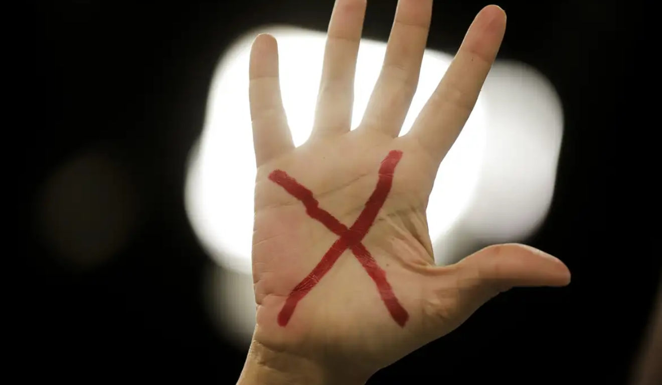 Imagem de uma mão com um X desenhado.