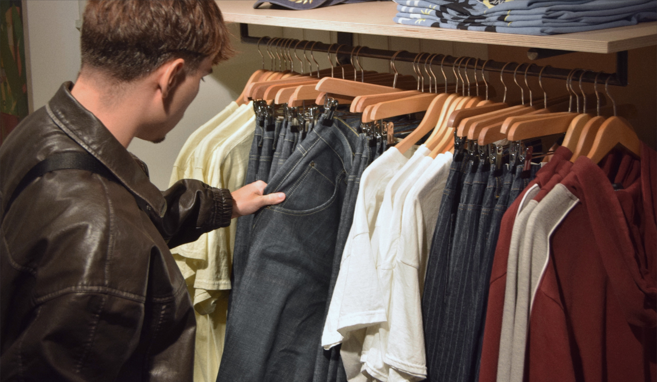 Imagem ilustrativa de homem branco vendo roupas em uma loja. Roupas são os itens com maior expectativa de vendas na Black Friday 2025 de Curitiba.
