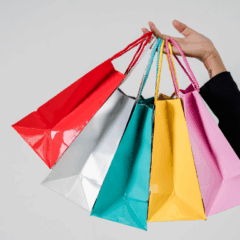 Imagem ilustrativa de mão de pessoa branca com sacolas coloridas, representando as vendas da Black Friday 2025 em Curitiba.