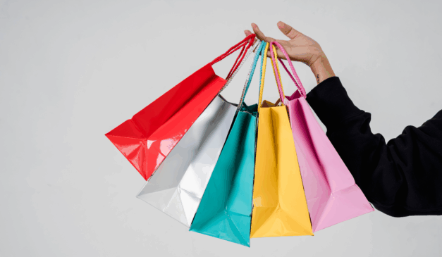Imagem ilustrativa de mão de pessoa branca com sacolas coloridas, representando as vendas da Black Friday 2025 em Curitiba.