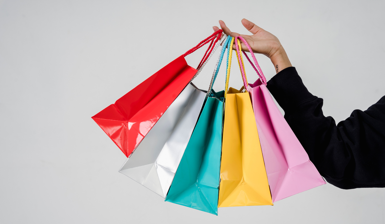Imagem ilustrativa de mão de pessoa branca com sacolas coloridas, representando as vendas da Black Friday 2025 em Curitiba.