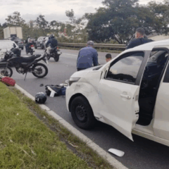 Cena do acidente na Linha Verde, em Curitiba, que envolveu tr&ecirc;s ve&iacute;culos. Um deles, o Fiat Uno branco, aparece em primeiro plano, com a moto da v&iacute;tima logo em frente, no ch&atilde;o.