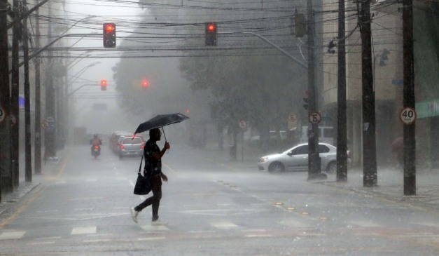 pessoa andando na chuva para ilustrar alerta laranja de tempestades no paraná