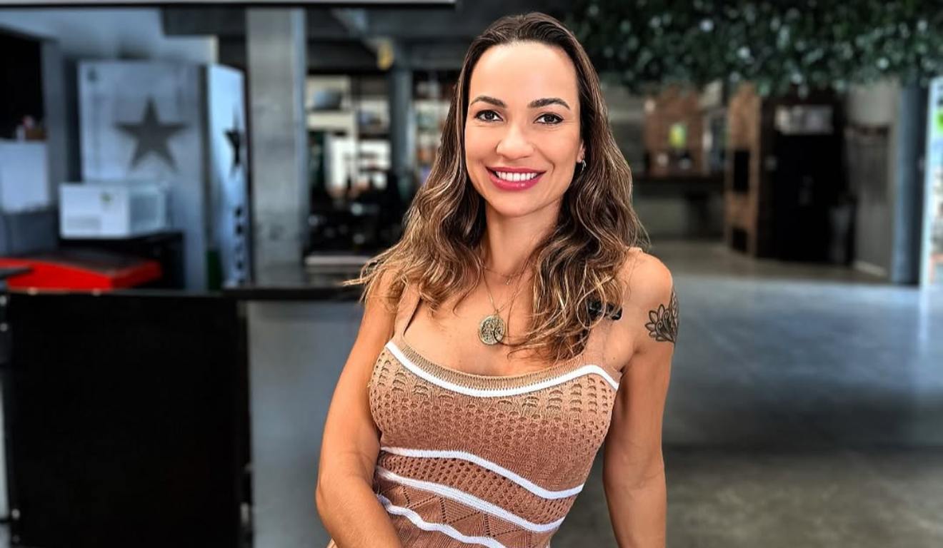 Aline Dalmolin em foto de perfil, usando um vestido bege com branco