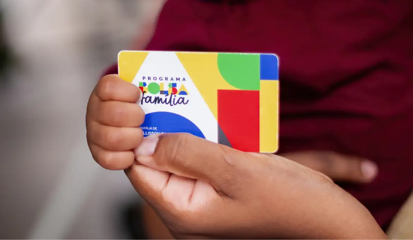 Pessoa negra segurando o cartão do Bolsa Família; calendário de pagamentos do programa em 2026 foi divulgado pelo MDS.