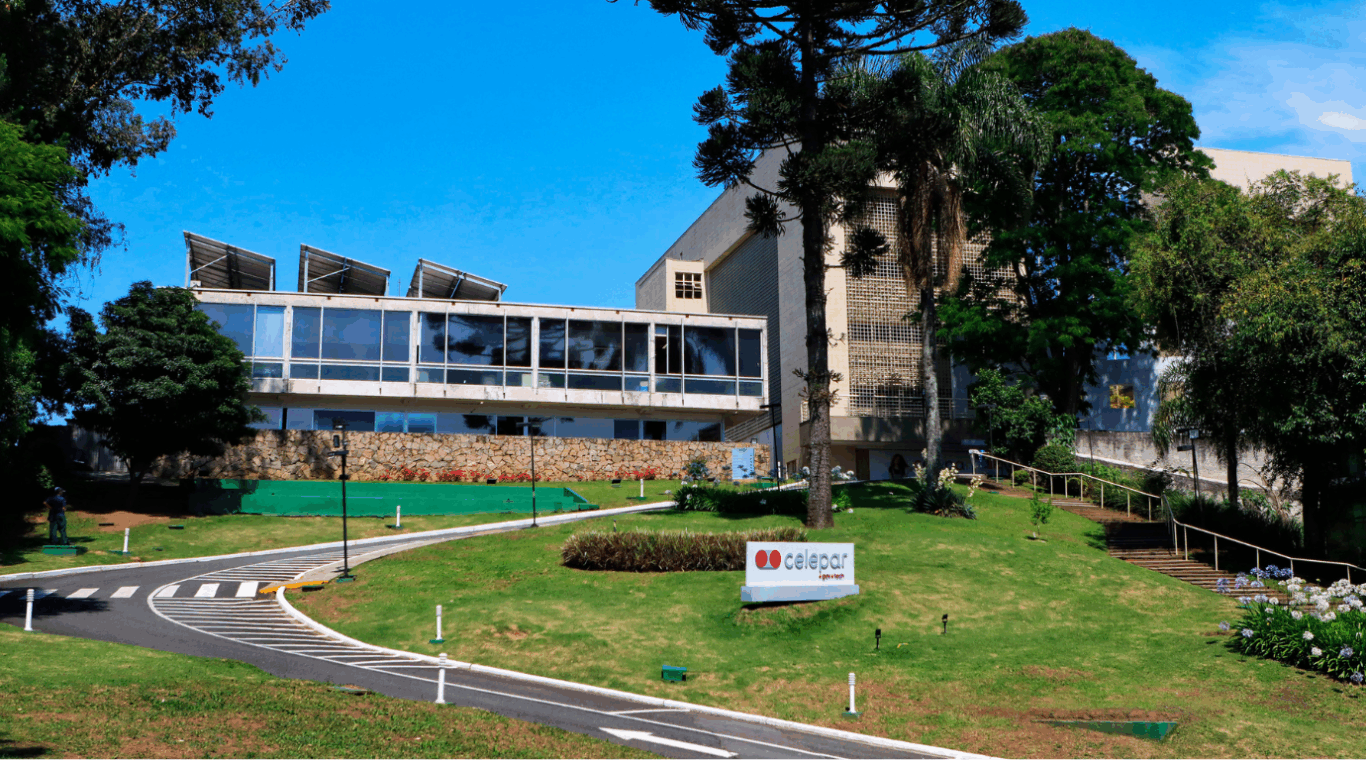 fachada da celepar, com o gramado, prédio ao fundo e céu azul