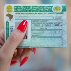 Mão feminina mostra uma carteira nacional de habilitação, CNH