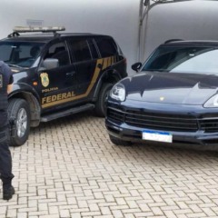 Policial federal de costas ao lado de carro de alto valor apreendido em operação