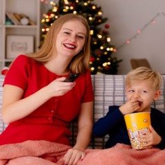 mãe e criança assistindo filme com decoração natalina ao redor